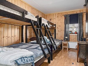 A bunk bed room with wooden walls and a small table with a plant. - 4 Star Holiday Home in Noresund (Krodsherad)