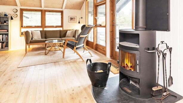 A cozy living room with a fireplace, wooden floors, and large windows. - 6 Person Holiday Home in Albaek (Aalbaek)