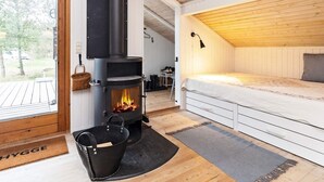 A cozy room with a wood-burning stove, a bed, and a view of the outdoors. - 6 Person Holiday Home in Albaek (Aalbaek)