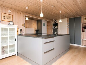 A modern kitchen with a central island, wooden ceiling, and pendant lighting. - 4 Star Holiday Home in Ulfborg (Ulfborg)