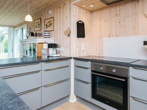 Una cocina moderna con armarios grises, horno empotrado y cafetera sobre la encimera.