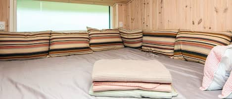 A cozy room with a large bed, striped pillows, and a wooden ceiling.