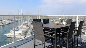 Ein Essbereich mit Tisch und Stühlen mit Blick auf eine Marina und zahlreiche Boote.