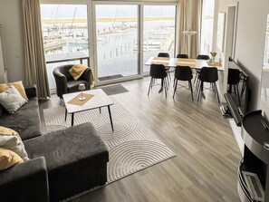 A modern living room with a sofa, a coffee table, and a dining area with chairs and a table.