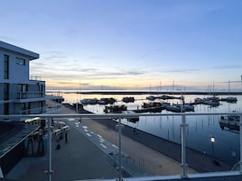 En lysthavn med fortøjede både, en bygning med balkon og en klar himmel.