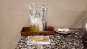 Una encimera de baño con una botella de gel de ducha, un cepillo de dientes y un jabonera.
