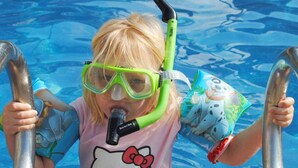 Een kind in een zwembad, dat snorkelt met een snorkel.