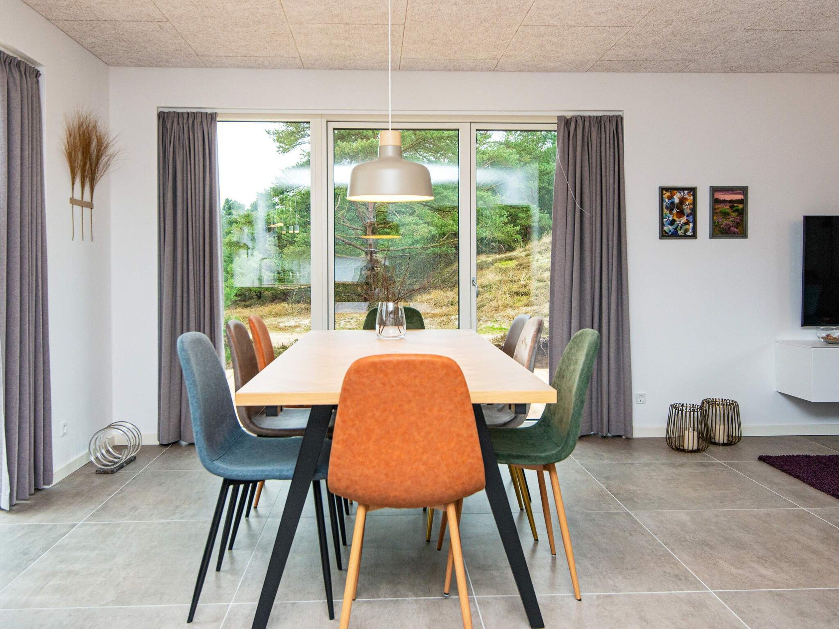 Ein stilvoller Essbereich mit großem Tisch, Stühlen und Blick auf Grünfläche.