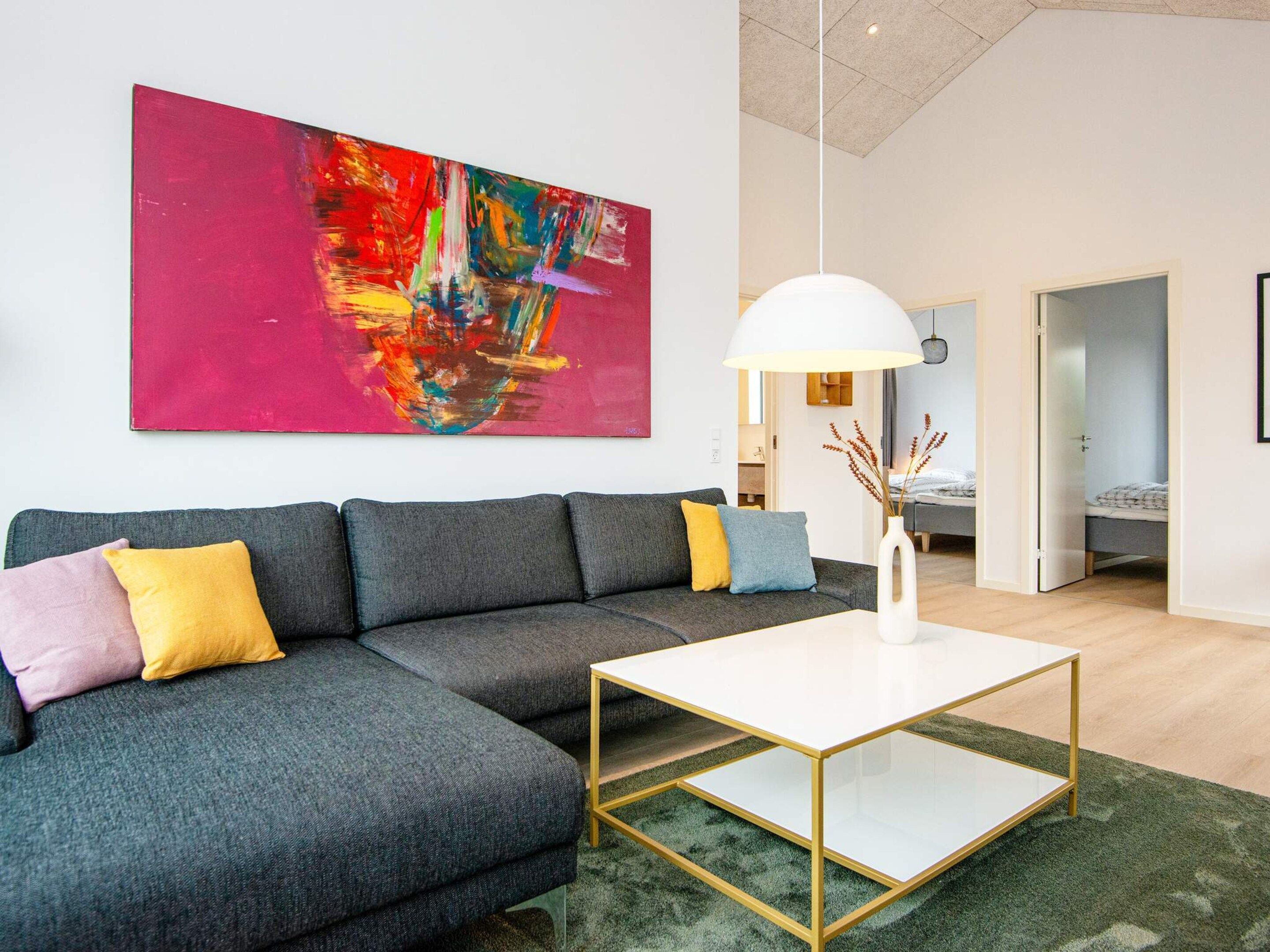 Ein modernes Wohnzimmer mit einem Ecksofa, einem weißen Couchtisch und einem großen abstrakten Gemälde an der Wand.