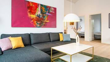 Ein modernes Wohnzimmer mit einem Ecksofa, einem weißen Couchtisch und einem großen abstrakten Gemälde an der Wand.