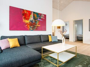 A modern living room with a sectional sofa, a white coffee table, and a large abstract painting on the wall. - 5 Star Holiday Home in Romo (Rømø)