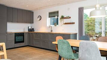 Una cocina moderna con armarios grises, encimera de madera y un comedor con mesa y sillas.