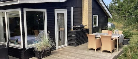 A modern house with a deck, a barbecue area, and outdoor furniture.