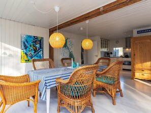 A dining area with wicker chairs, a striped tablecloth, and a large painting on the wall.