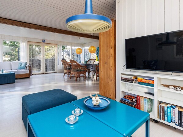 A modern living room with a blue table, a large TV, and a bookshelf.