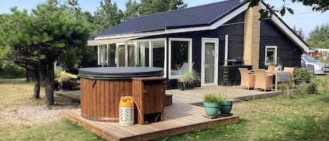 A house with a hot tub, outdoor seating, and a deck.