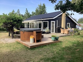 A house with a hot tub, outdoor seating, and a deck.