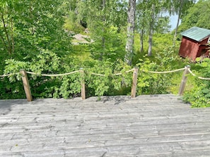 A wooden staircase leading up to a cabin surrounded by dense greenery and trees.