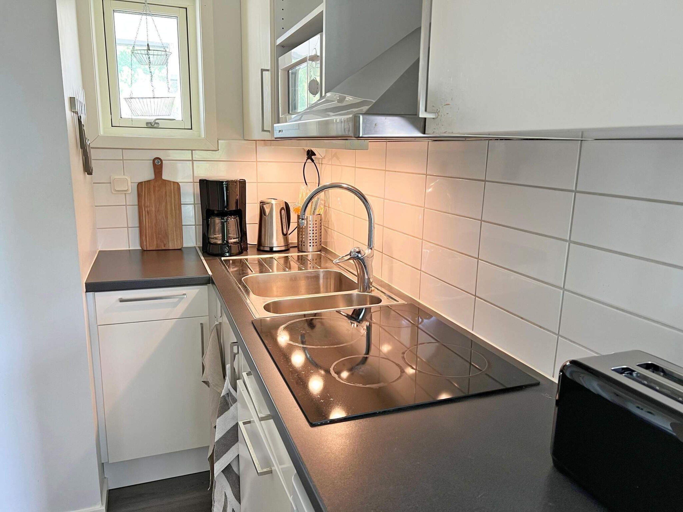 Eine moderne Küche mit Spüle aus Edelstahl, einem Backofen und einer Kaffeemaschine.