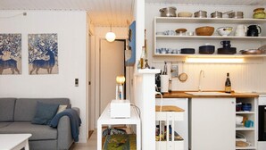 A modern living room with a grey sofa, a small white table, and a wicker basket. - 4 Person Holiday Home in Hejls (Hejls)