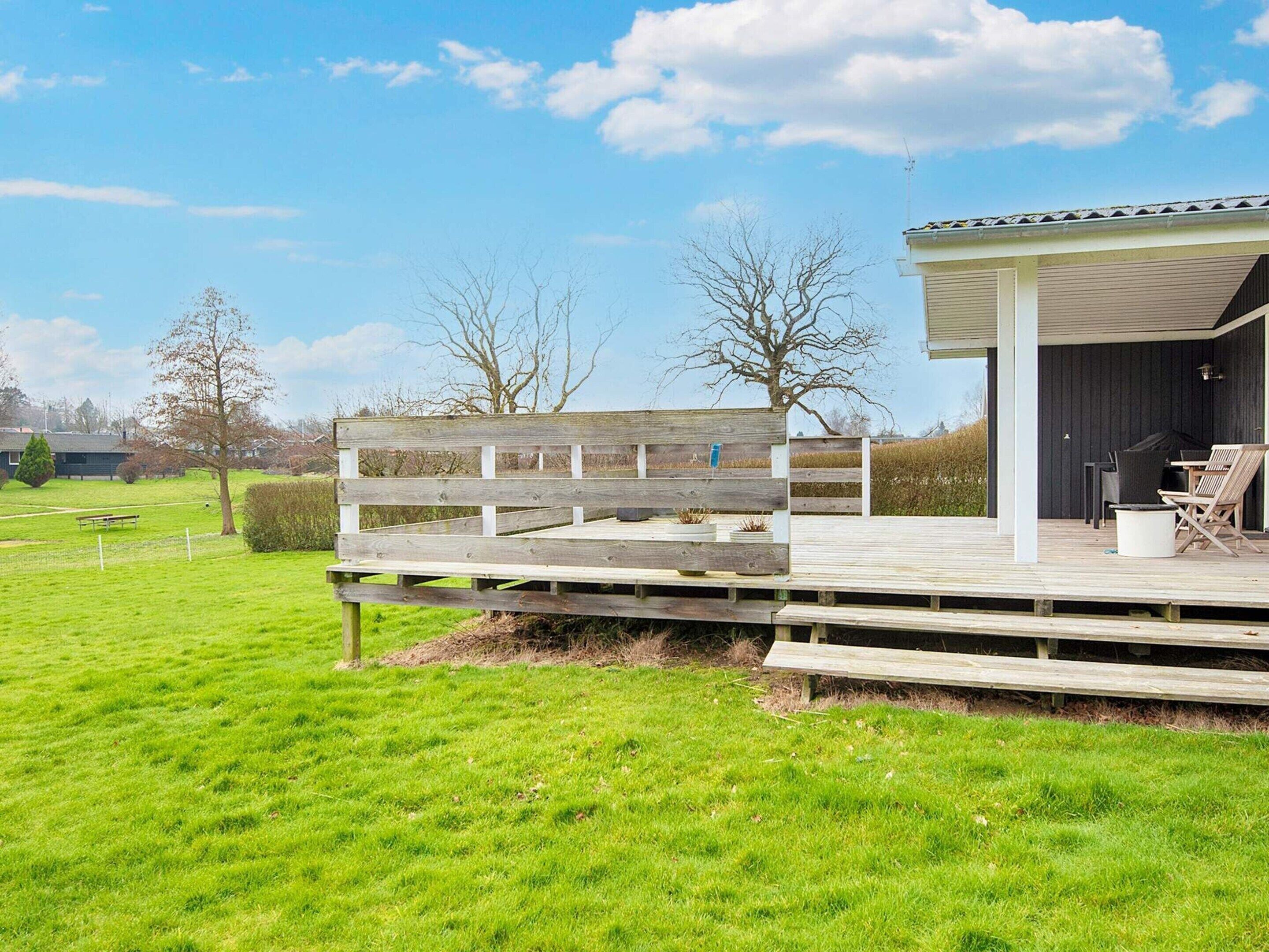 A wooden deck with a covered outdoor area, a bench, and a small table.