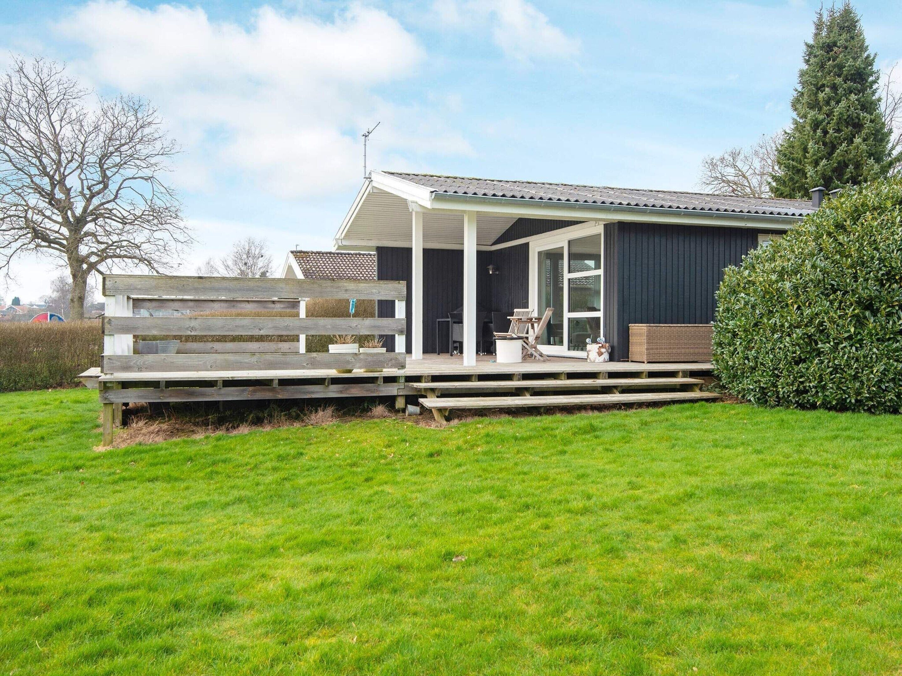 A modern house with a covered porch, a wooden deck, and a well-maintained lawn.