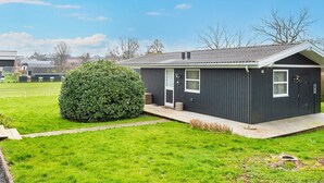 A single-story house with a dark exterior, a small front porch, and a well-maintained lawn. - 4 Person Holiday Home in Hejls (Hejls)