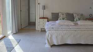 A bedroom with a bed, bedside tables, a lamp, and a door leading to another room. - 4 Person Holiday Home in Skanes-fagerhult (Skånes Fagerhult)