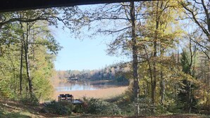A view of a lake surrounded by trees, with a wooden bench and a small structure in the foreground. - 4 Person Holiday Home in Skanes-fagerhult (Skånes Fagerhult)