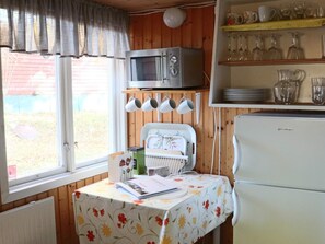 Une cuisine compacte équipée d’un four à micro-ondes, d’un réfrigérateur et d’une table recouverte d’une nappe à motifs floraux.