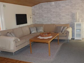 A living room with a beige sectional sofa, a wooden coffee table, and a white cabinet. - 4 Person Holiday Home in Skanes-fagerhult (Skånes Fagerhult)
