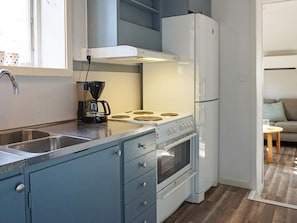 A compact kitchen with a stove, sink, and a coffee maker.