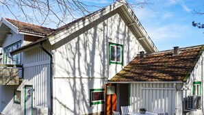 A white wooden house with a sloped roof, a small porch with chairs, and a window with green trim. - 3 Person Holiday Home in Hunnebostrand-by Traum (Hunnebostrand)