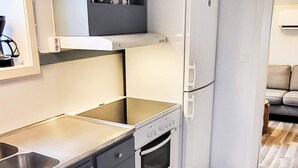 A compact kitchen with a built-in oven, a stovetop, and a refrigerator. - 3 Person Holiday Home in Hunnebostrand-by Traum (Hunnebostrand)