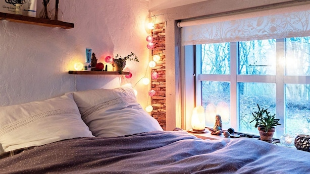 A cozy bedroom with a bed, a nightstand, a window with a view of trees, and a wall-mounted shelf with decorative items. - 6 Person Holiday Home in Lokken (Lokken)
