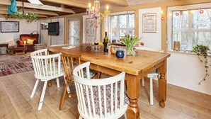 A cozy dining area with a wooden table, white chairs, and a chandelier. - 6 Person Holiday Home in Lokken (Lokken)