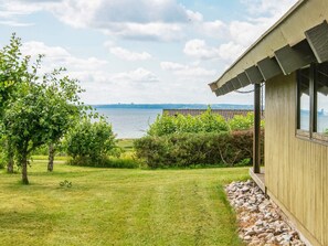 A building with a view of a body of water, surrounded by greenery and a clear sky. - 6 Person Holiday Home in Knebel (Knebel)
