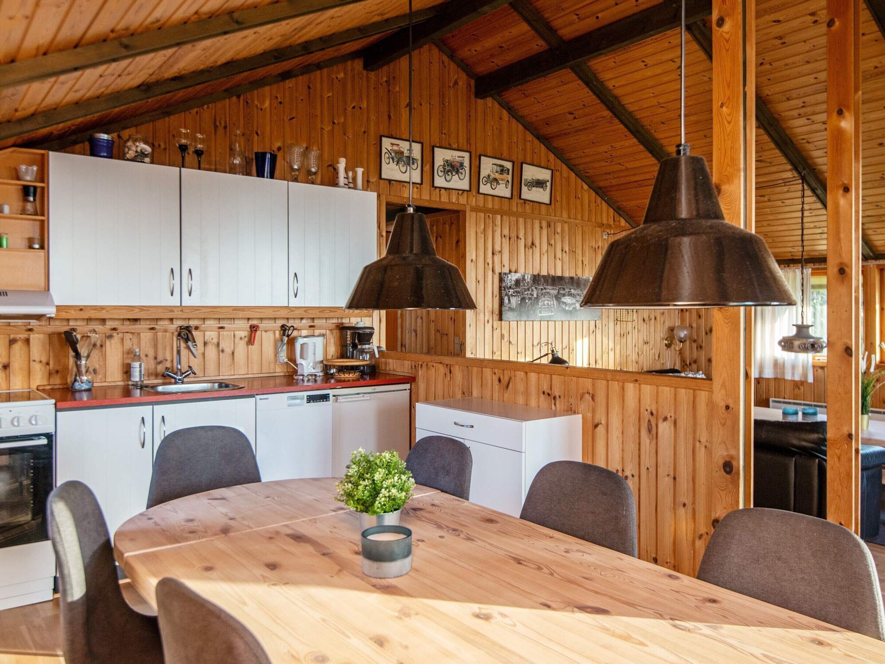 Interior em madeira com cozinha, sala de jantar e teto com vigas aparentes.