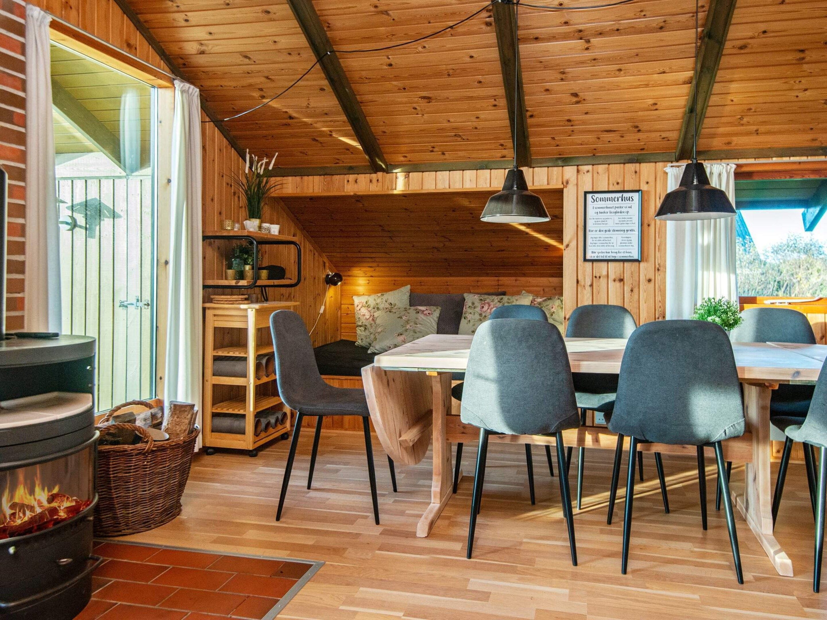 A cozy cabin interior with a dining area, a fireplace, and a view of the outdoors.