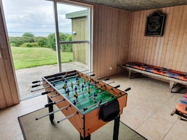 Una mesa de fútbol de mesa en una habitación con un banco y vistas al exterior.