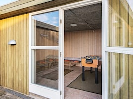 Habitación con puerta de cristal corredera que da a un espacio exterior, mesa de fútbol de mesa y cama con colcha estampada.