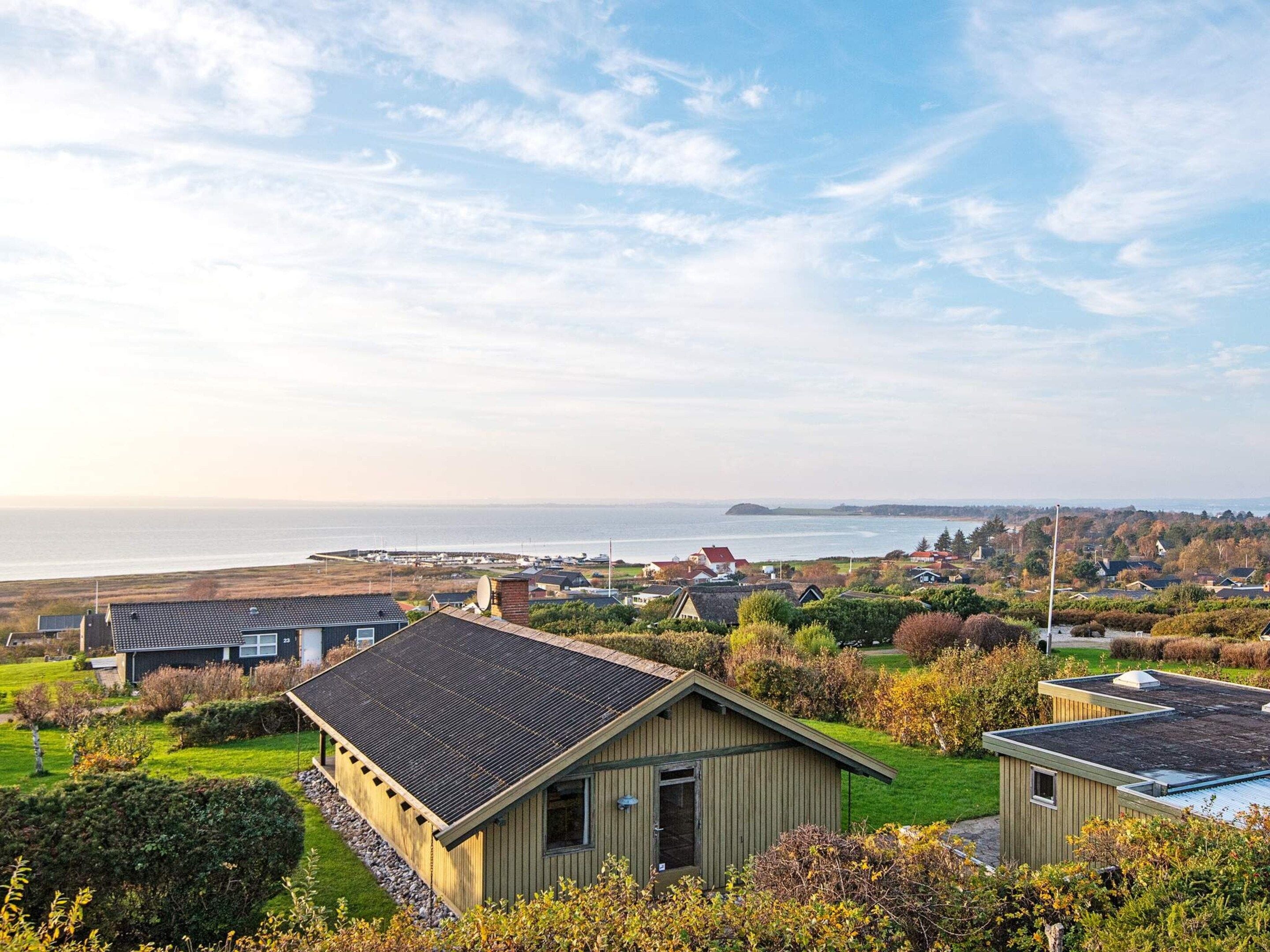 A coastal residential area with houses, a clear sky, and a view of the sea.