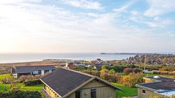A coastal residential area with houses, a clear sky, and a view of the sea.