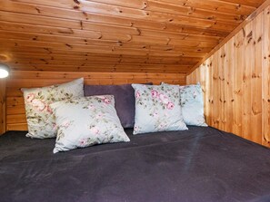 A room with a wooden ceiling and a bed with floral bedding. - 6 Person Holiday Home in Knebel (Knebel)