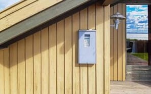 A wooden exterior wall with a utility box and a pathway leading to a door. - 6 Person Holiday Home in Knebel (Knebel)