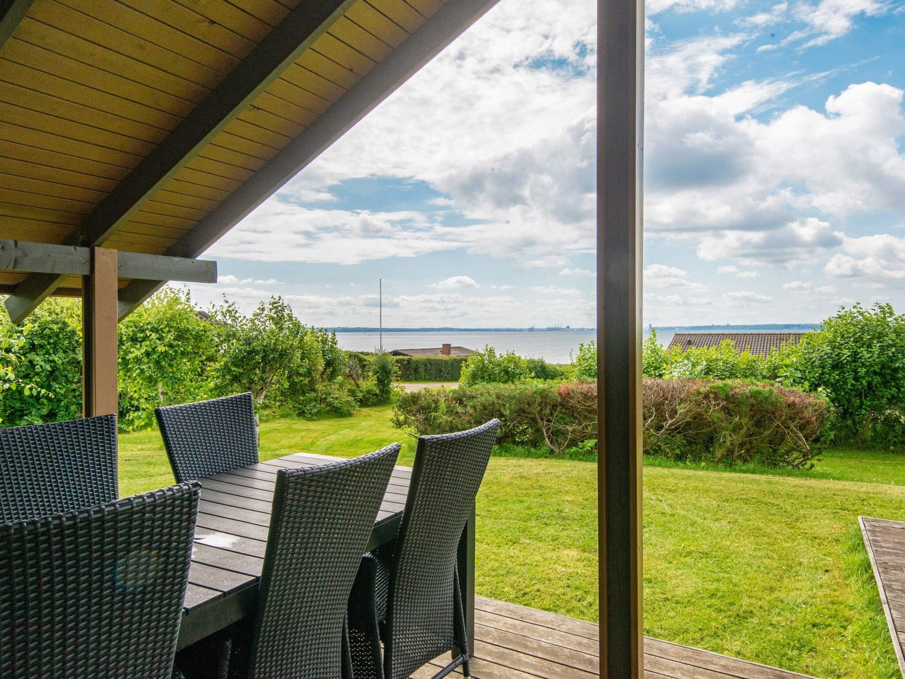 An outdoor patio with a view of the sea and a bridge in the distance.