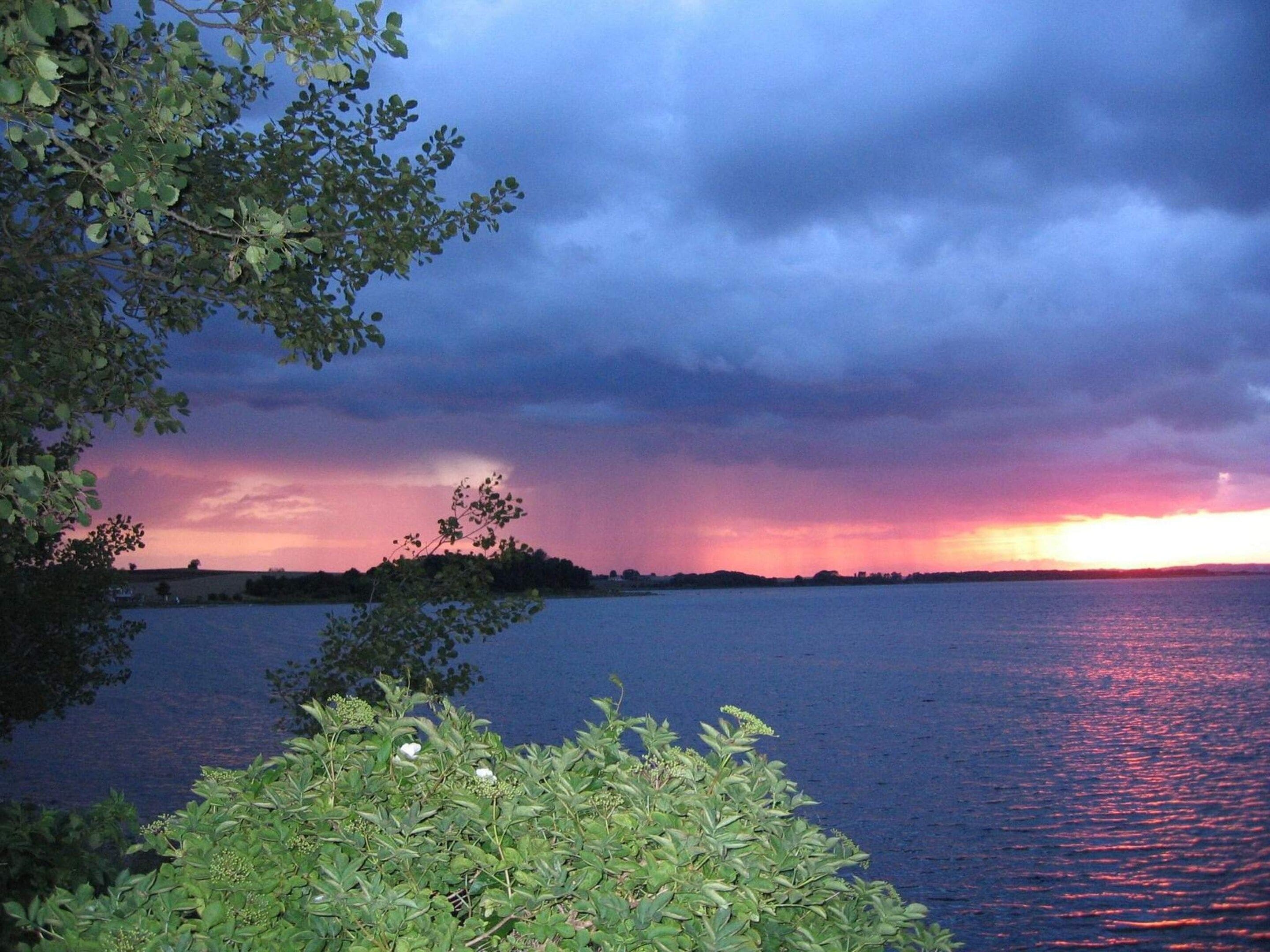 Une étendue d’eau d’où l’on peut apercevoir une côte lointaine et un ciel nuageux.
