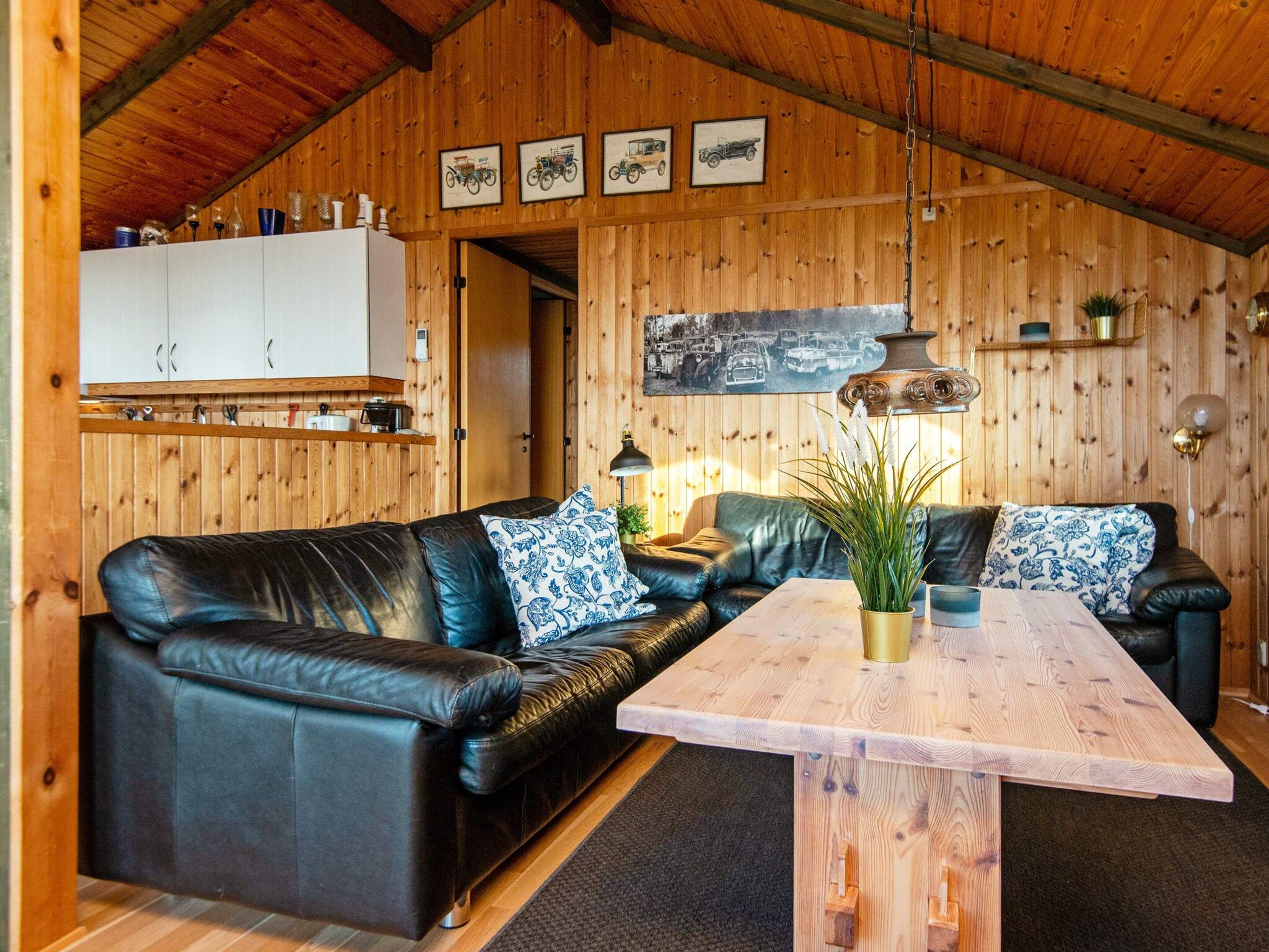 Una sala acogedora con un sofá de cuero negro, una mesa de centro de madera y una mesa de comedor.