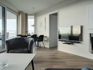 A modern living room with a flat-screen TV, a dining area with chairs, and a large window. - 5 Star Holiday Home in Wendtorf (Wendtorf)