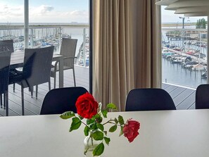 A table with a vase of roses, overlooking a marina with boats. - 5 Star Holiday Home in Wendtorf (Wendtorf)